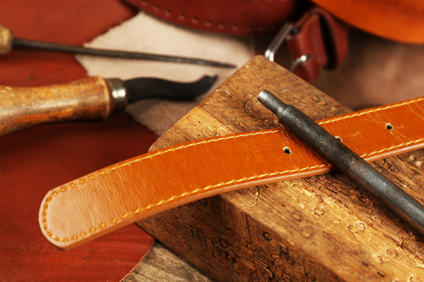 Craft tools with leather belt on table close up - Foto, Bild