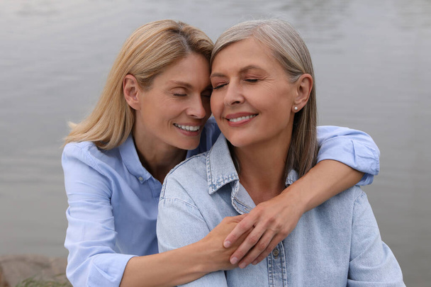 Happy mature mother and her daughter hugging near pond - Valokuva, kuva
