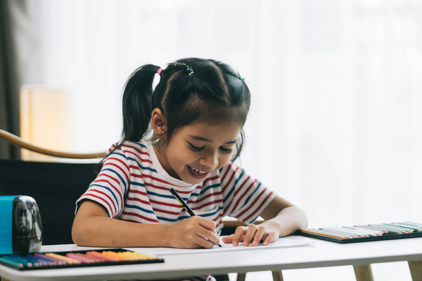 mignon asiatique enfant fille dessin avec crayons à la maison. - Photo, image