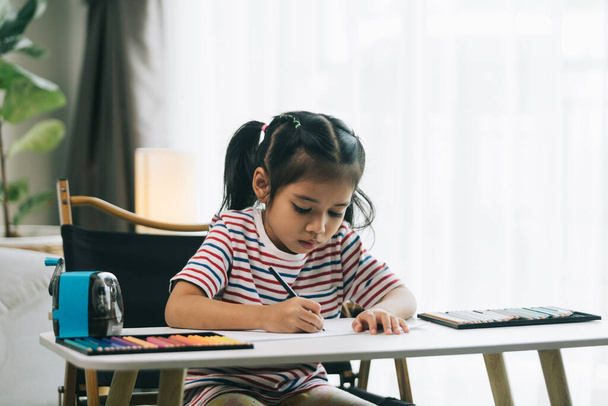 Kleine asiatische Mädchen zeichnen mit Bleistiften im Wohnzimmer zu Hause - Foto, Bild