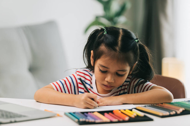 selectieve focus van schattige aziatische kind tekening met kleurpotloden thuis - Foto, afbeelding
