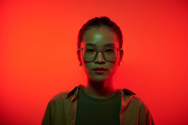Porträt eines ernsthaften jungen Hackers, der im Rotlicht steht und in die Kamera blickt - Foto, Bild