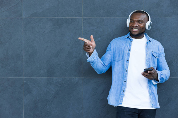 スタイリッシュで若いアフリカ系アメリカ人男性がヘッドフォンで音楽を聴く - 写真・画像