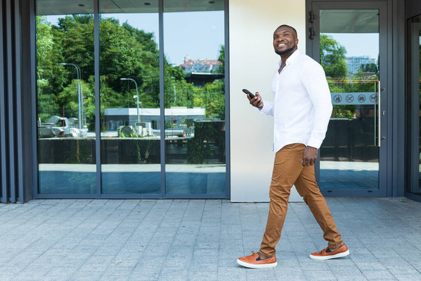 Een jonge, succesvolle Afro-Amerikaanse man met een smartphone in zijn handen - Foto, afbeelding