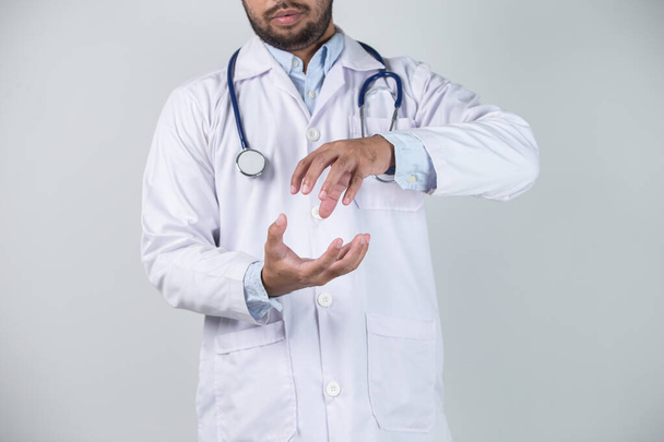 Nahaufnahme eines männlichen Arztes mit Tabletten in den Händen, isoliert auf grauem Hintergrund - Foto, Bild