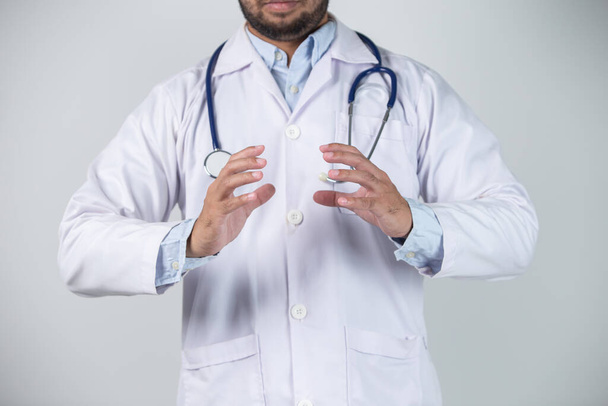 Nahaufnahme eines männlichen Arztes mit Stethoskop auf grauem Hintergrund - Foto, Bild