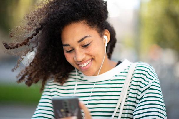 Muotokuva onnellinen nuori nainen kuulokkeet katsot matkapuhelinta - Valokuva, kuva