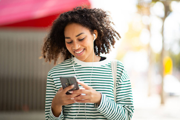 Portret uśmiechnięta młoda kobieta z telefonem komórkowym i słuchawkami - Zdjęcie, obraz