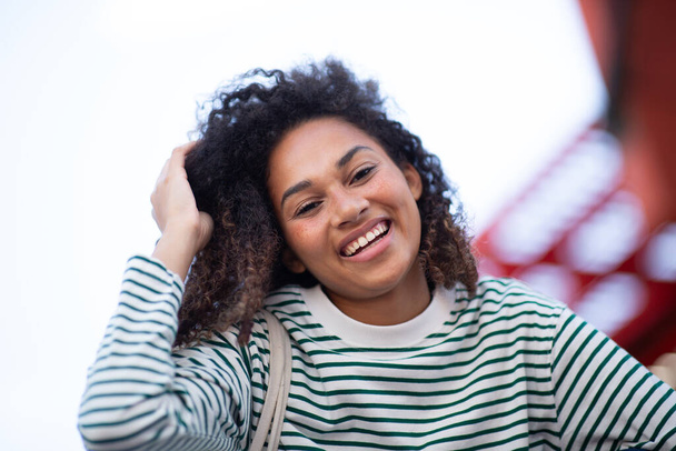 Портрет улыбающейся молодой женщины с вьющимися волосами - Фото, изображение