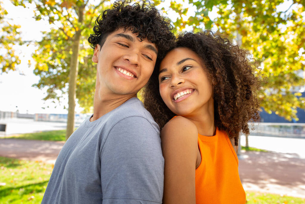 Muotokuva hymyilevä nuori pari seisoo takaisin puistossa - Valokuva, kuva