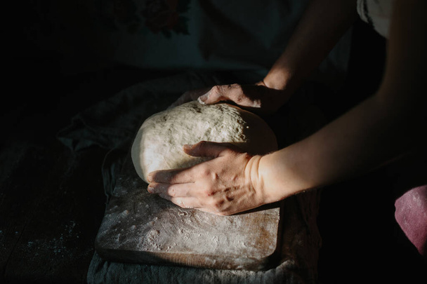 伝統的なウクライナの服の女性はパン生地をひざまずきます. - 写真・画像
