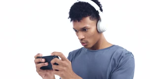 Άνθρωπος, ακουστικά και smartphone, βιντεοπαιχνίδι και τεχνολογία με online streaming σε λευκό φόντο. Esports, gamer σε στούντιο και internet, συνδεσιμότητα και χρήση τηλεφώνου με ήχο και ανταγωνισμό. - Πλάνα, βίντεο
