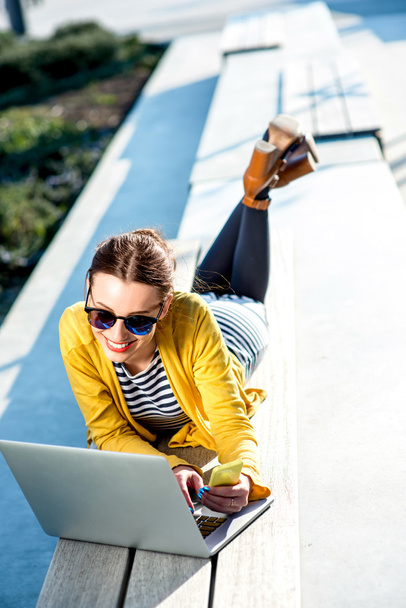 Woman with laptop and phone outdoors - Photo, image