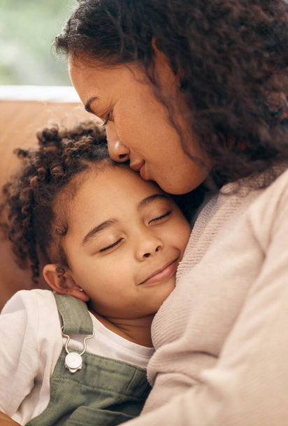 Love, kiss and mother hug girl child on a sofa with trust, support and bond at home together. Family, relax and kid embrace mom in a living room peaceful, protection or safety and security in a house. - Photo, Image