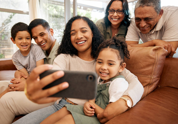 Famiglia numerosa, selfie e nonni con bambini sul divano per le vacanze, amano e si rilassano insieme a casa. Persone interrazziali, madre e padre con bambini sorridono sul divano per foto profilo. - Foto, immagini