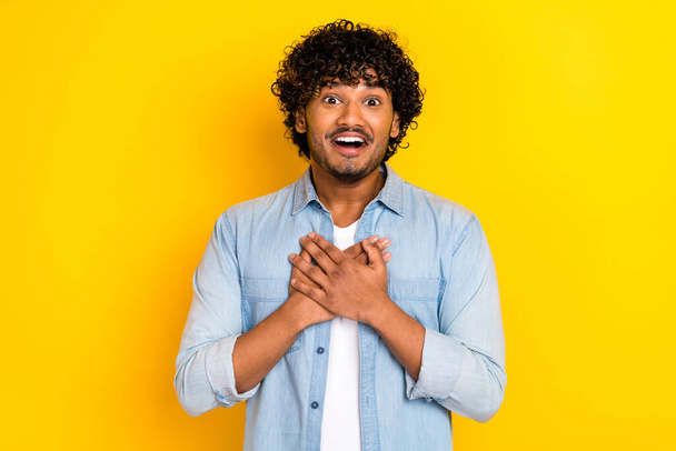 Portrait of impressed man with wavy hairstyle wear jeans shirt arms on chest astonished staring isolated on yellow color background. - Foto, afbeelding