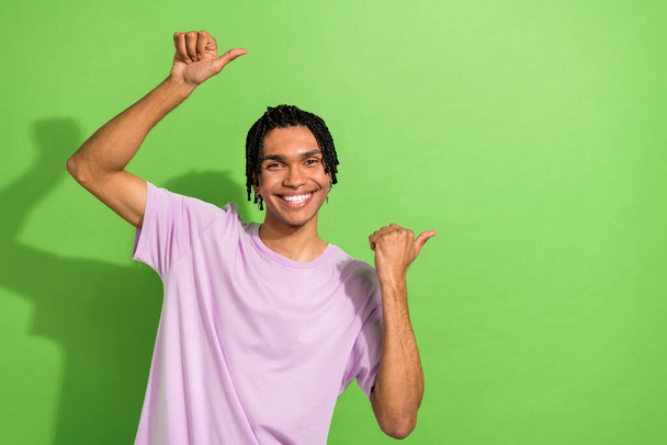 Portrait of cheerful guy youth generation directing thumbs empty space mockup novelty banner isolated green color background. - 写真・画像