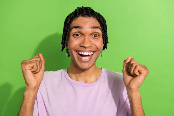Portrait of overjoyed glad person raise fists toothy smile attainment accomplishment isolated on green color background. - Photo, Image