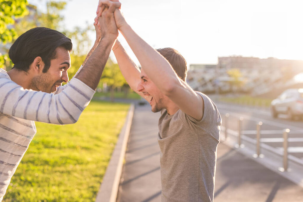Deux jeunes hommes multiethniques en plein air célébrant le succès - Photo, image