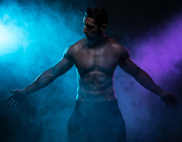 Silhouette hemdlos muskulösen Mann posiert in Rauch - Foto, Bild