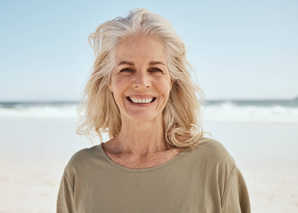Portrait, beach and senior woman with a smile, retirement and travel with tourist, summer vacation and wellness. Face, old person and traveler on seaside holiday, Canada and weekend break for peace. - Photo, Image