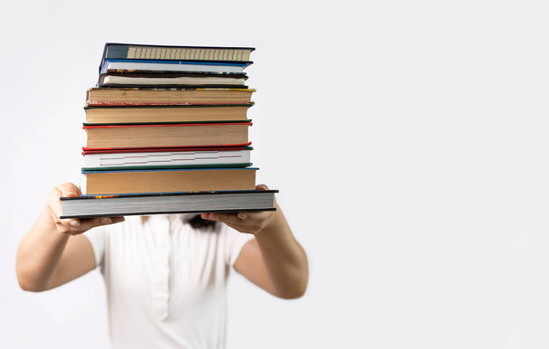Dziewczyna trzyma stos książek na białym tle. Koncepcja edukacji. Gotowy do ciężkiej nauki! - Zdjęcie, obraz