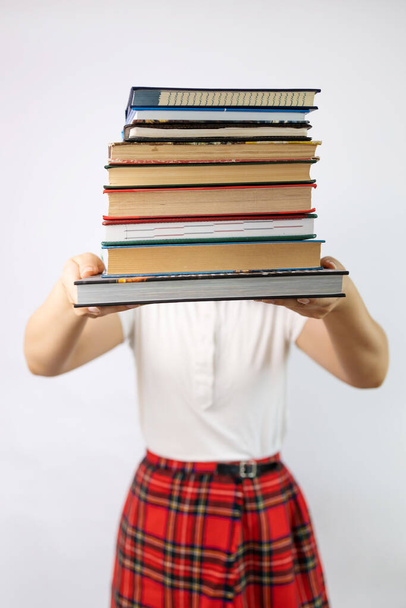 Κορίτσι που κρατάει μια στοίβα από βιβλία σε λευκό φόντο. Εκπαιδευτική ιδέα. Έτοιμος να μελετήσει σκληρά! - Φωτογραφία, εικόνα