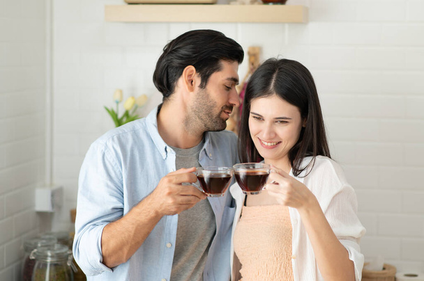 Счастливая влюбленная пара пьет кофе на кухне утром дома - Фото, изображение