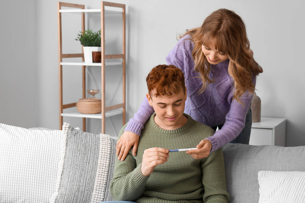 Genç bir kadın evde erkek arkadaşına hamilelik testi gösteriyor. - Fotoğraf, Görsel