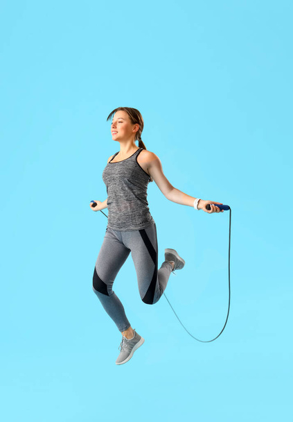 Desportivo jovem mulher pulando corda no fundo azul - Foto, Imagem