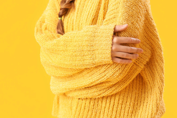 jonge vrouw in warme trui en bril knuffelen zichzelf op gele achtergrond - Foto, afbeelding