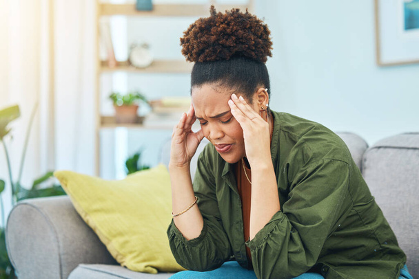 Žena, bolest hlavy a bolest na pohovce pro stres, závratě a výzva duševního zdraví doma. Smutná africká osoba frustrovaná z migrény, úzkosti nebo deprese únavy, dluhu nebo závratě v obývacím pokoji. - Fotografie, Obrázek
