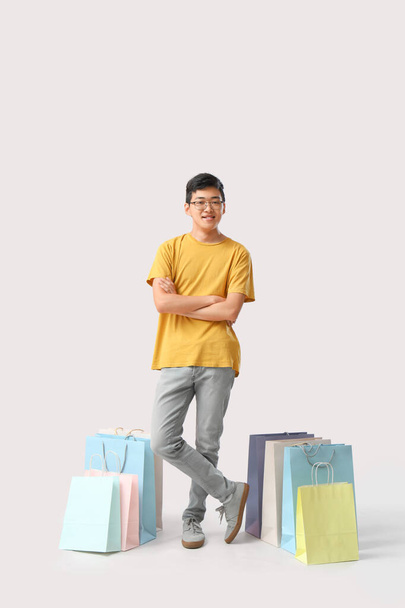 Giovane asiatico uomo con shopping bags su sfondo bianco - Foto, immagini