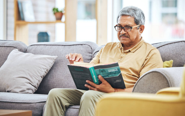 Domov, relaxovat a starší muž s knihou, důchod a klid s příběhem v obývacím pokoji. Stařec, klidný a důchodce v salonku, románu nebo literatuře s koníčkem, svépomocí nebo čtením na pohovce. - Fotografie, Obrázek