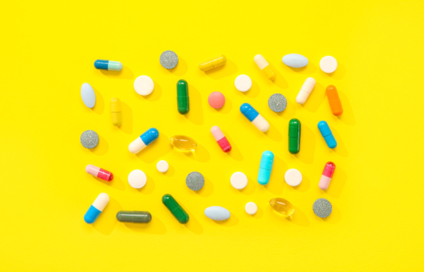 Diferentes píldoras sobre fondo amarillo - Foto, Imagen