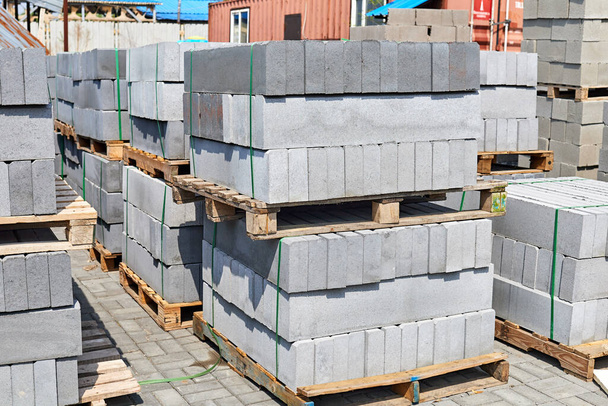 бетонные бордюры, сложенные на поддонах на внешнем складе - Фото, изображение