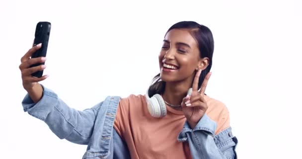 Peace sign, happy woman or influencer taking a selfie in studio with fashion or smile on social media. Post, gen z or cool Indian girl taking a photo, vlog or picture isolated on white background. - Footage, Video