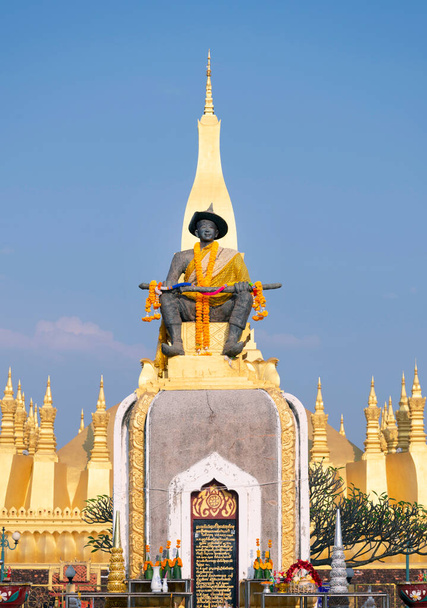 Cerca de la entrada, estatua del antiguo rey Setthathirat, la Stupa estableció el siglo III dC, color dorado vibrante que brilla a la luz del sol.Un importante monumento nacional en Laos y un símbolo nacional. - Foto, imagen