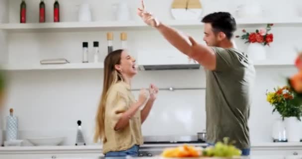 Energy, happy and couple dance in the kitchen to music, playlist or radio at modern apartment. Smile, love and young man and woman moving, bonding and moving to a song or album together at home - Footage, Video