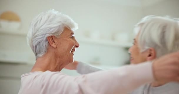 Knuffel, welkom en senior vriendinnen in de woonkamer van hun huis tijdens een bezoek in pensionering. Glimlach, liefde en een gelukkig bejaarde die haar zus omarmt terwijl ze zich samen opgewonden voelt. - Video