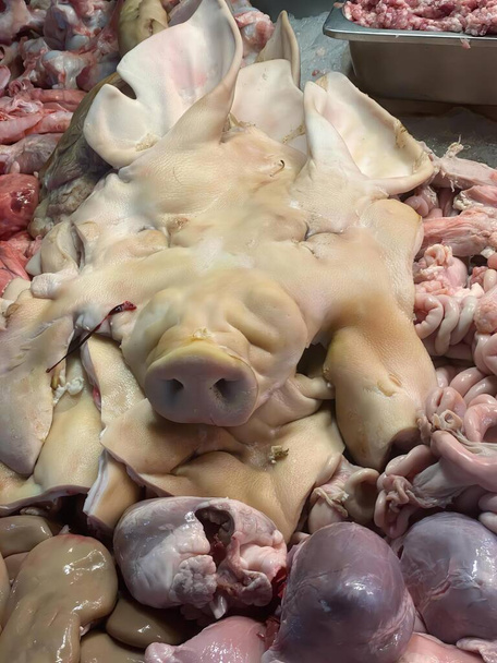 Üstünde domuz kafası olan bir et yığını fotoğrafı, kasaptan alınmış çiğ tavuk ve diğer satılık etler.. - Fotoğraf, Görsel