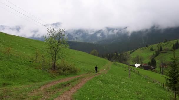 Um homem caminha ao longo da trilha para as cabanas nas montanhas - Filmagem, Vídeo