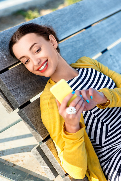 Vrouw met telefoon op zonnebank - Foto, afbeelding