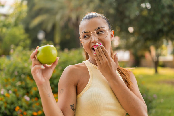 Junge hübsche Frau mit einem Apfel im Freien überrascht und schockiert - Foto, Bild