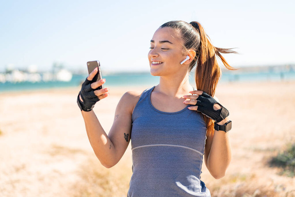Молода красива спортивна жінка в спортивному одязі і слухає музику з телефоном
 - Фото, зображення