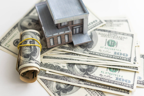 маленькая модель дома с банкнотами и ключами за много долларов. Страхование недвижимости. Инвестиции. Высокое качество фото - Фото, изображение