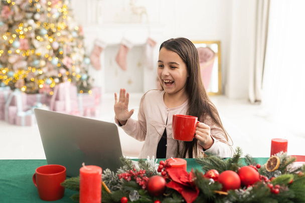 gelukkig meisje met behulp van laptop thuis tijdens kerst. - Foto, afbeelding