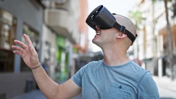 Молодий іспаномовний чоловік грає у відеогру, використовуючи окуляри віртуальної реальності на вулиці - Кадри, відео