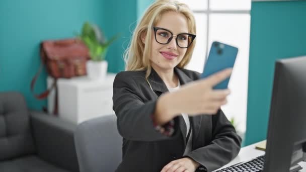 Νεαρή ξανθιά επιχειρηματίας κάνει selfie από smartphone εργασίας στο γραφείο - Πλάνα, βίντεο