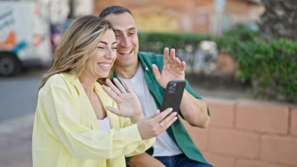 man en vrouw paar met video call zitten op bank in park - Video